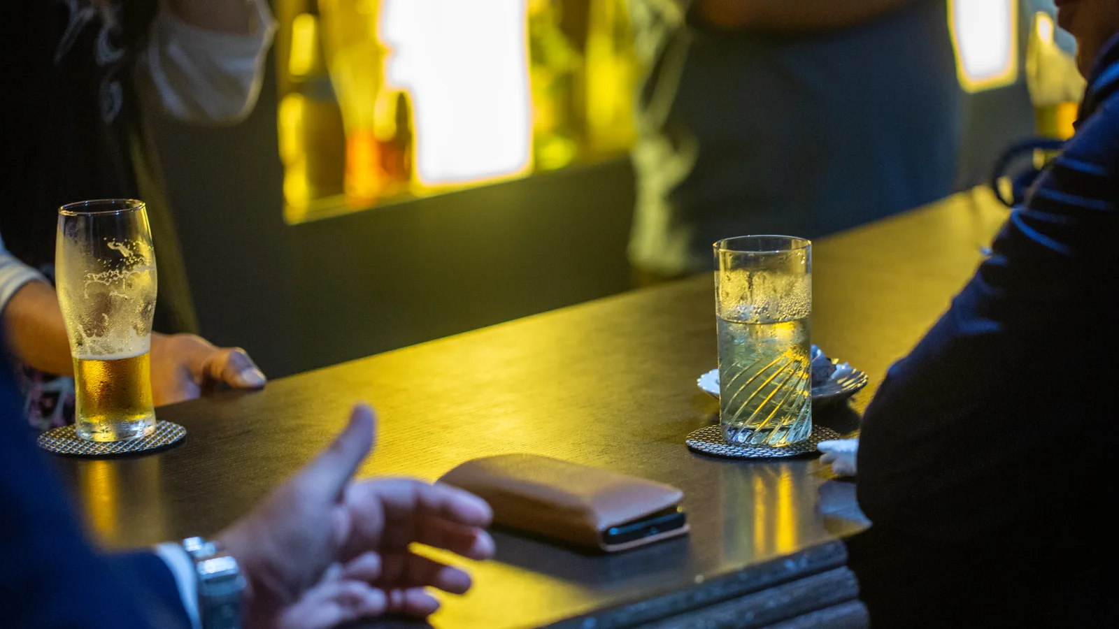 Bar SG様でお客様が会話を楽しむシーン。カウンターに並ぶビールとハイボール